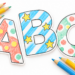 Bunte Druckbuchstaben A, B und C mit Punkten, Streifen und Sternen neben Farbstiften.